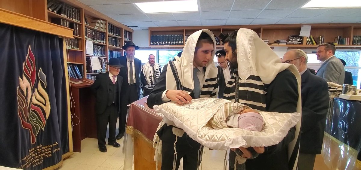 The baby carried in on a decorative pillow to begin the bris ceremony
