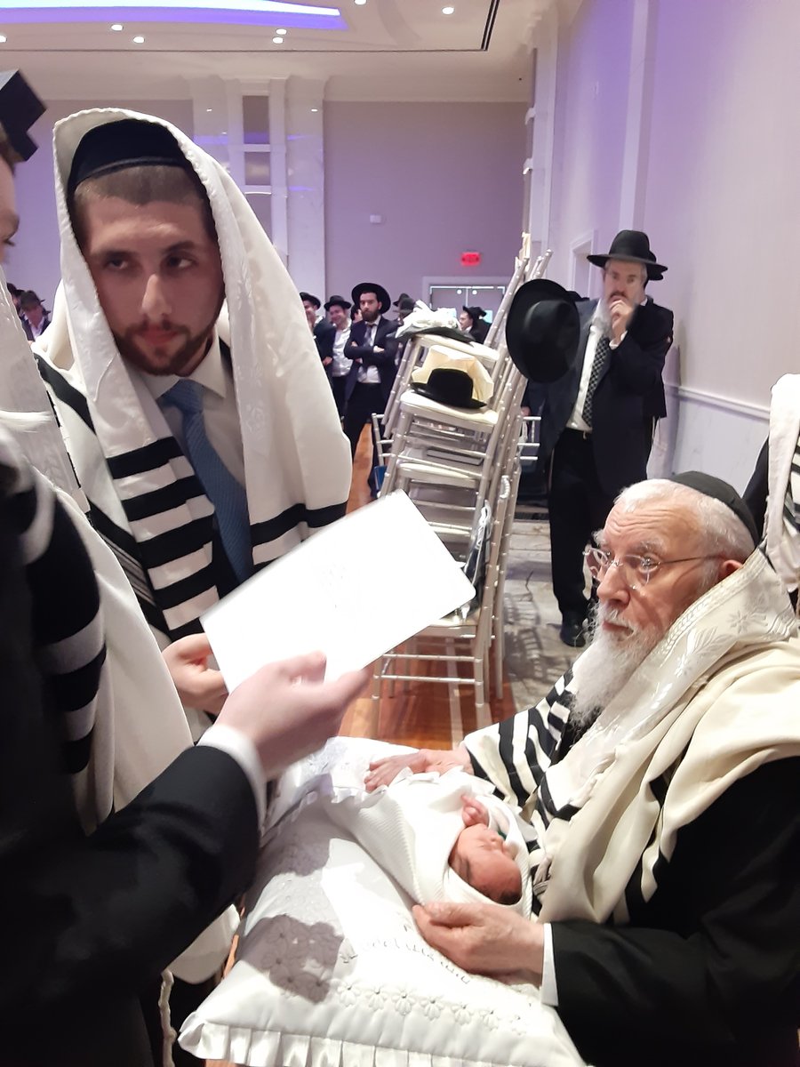 Reciting a blessing as the sandek holds the baby during the bris