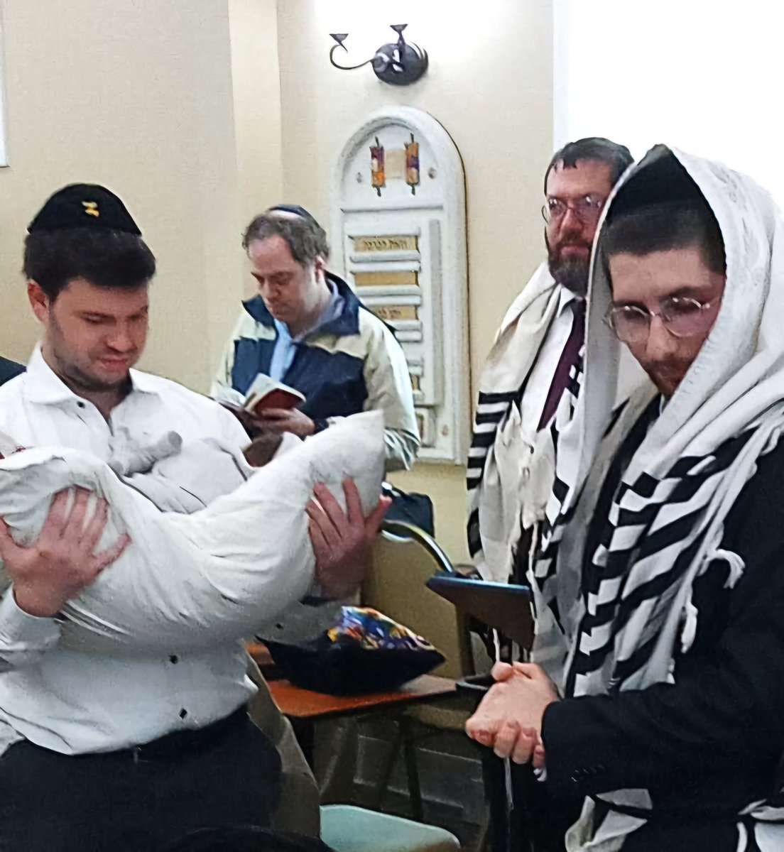 Family and guests surrounding the baby during the bris ceremony